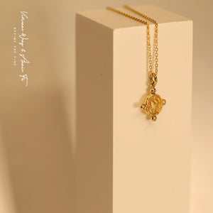 Yellow gold heart-shape coin necklace on a white object